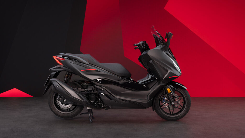 Scooter Honda Forza 350 noir, de profil, sur fond rouge et noir