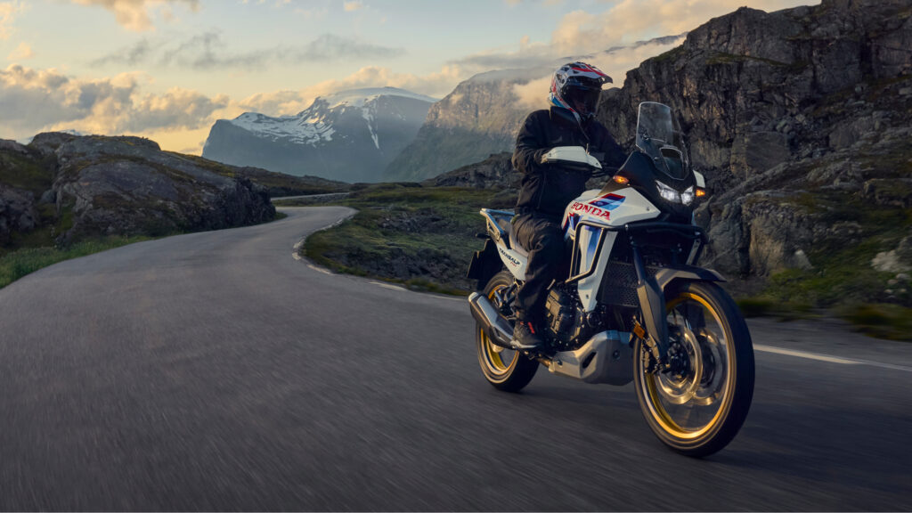 Honda XL750 Transalp sur une route de col, panorama de montagnes