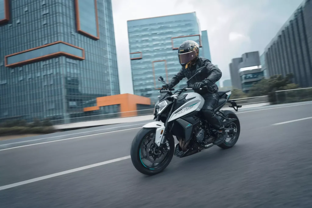 KOVE 450 R en ville, pilote en tenue sombre devant des immeubles