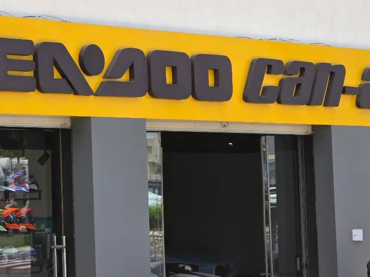 Enseigne jaune du magasin, portant les marques nautique et tout-terrain distribuées, au-dessus des vitrines du showroom