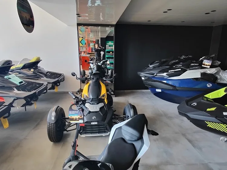 Intérieur du showroom : jet-skis alignés le long du mur sombre, un trois-roues au centre et une moto au premier plan