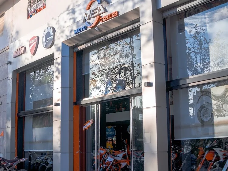Façade du magasin MSA Moto Center de jour, enseigne et logos constructeurs au-dessus des vitrines, quads garés devant l’entrée