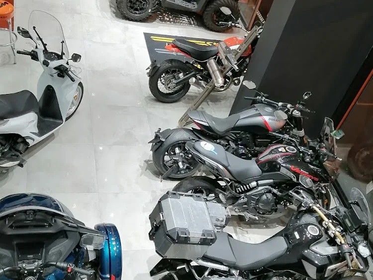 Vue plongeante sur le showroom : quad, scooters, roadsters et trails équipés de valises alu, alignés sur toute la longueur