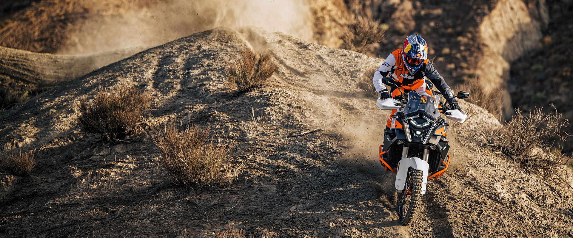 Pilote en tenue tout-terrain sur une moto d'aventure KTM, en franchissement dans le désert