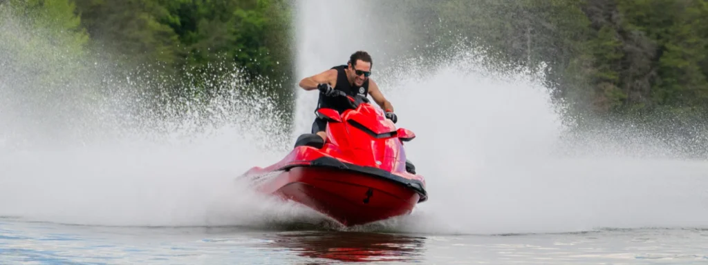 Jet-ski Yamaha GP1800R SVHO rouge vu de loin, sillage sur un lac bordé d'arbres