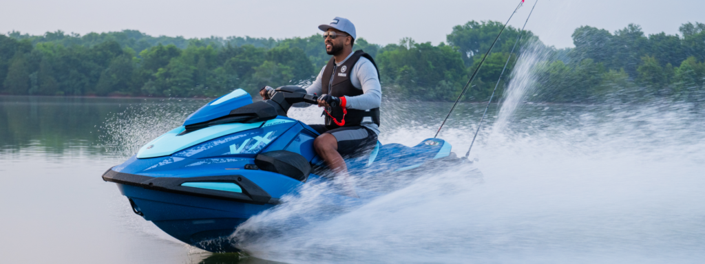 Jet-ski Yamaha VX Cruiser bleu en virage, gerbe d'eau sur un lac