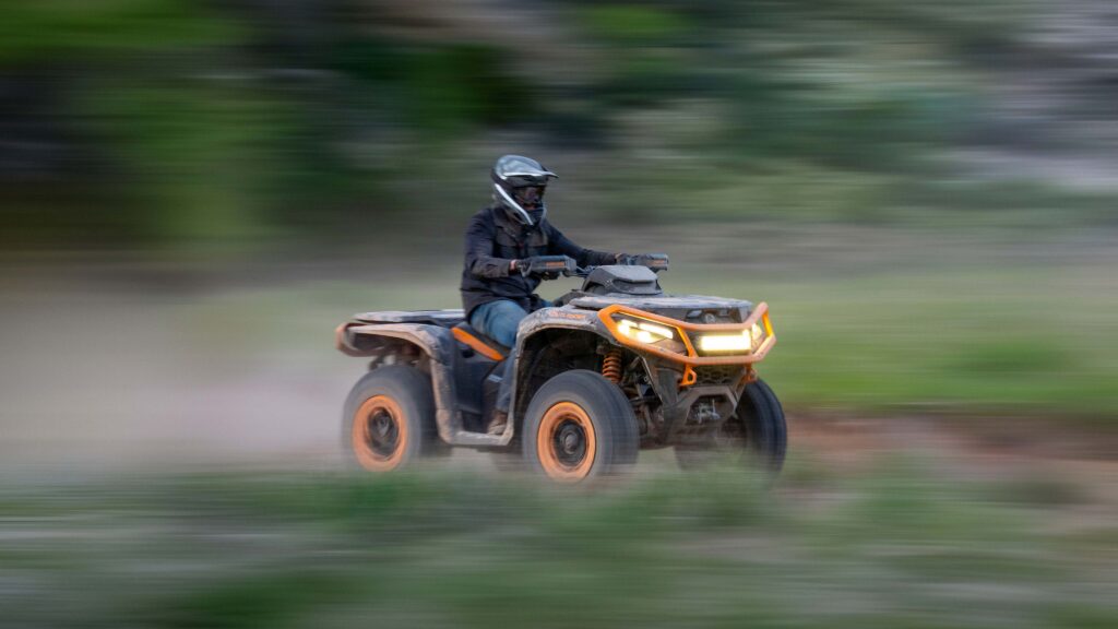 Can-Am Outlander XT-P 1000R lancé sur un chemin de terre, pilote casqué