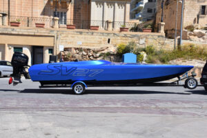 Bateau Chaudron SV 27 à coque bleue sur sa remorque, vu de profil