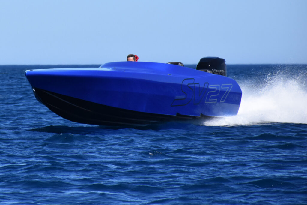 Chaudron SV 27 bleu planant au large, gerbe d'eau à l'arrière