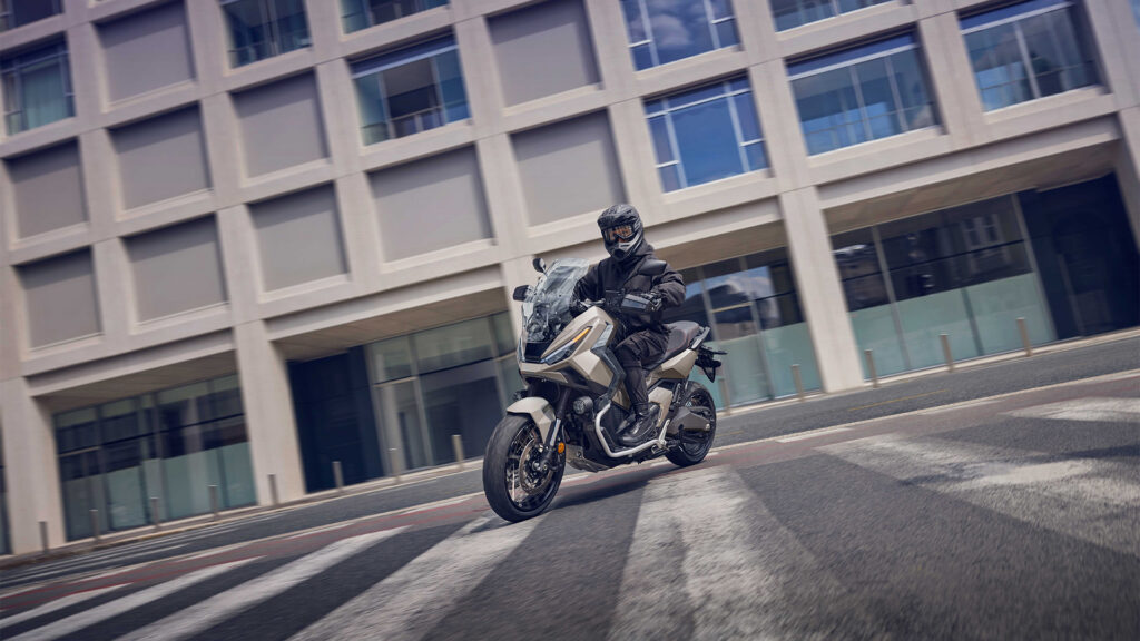 Honda X-ADV 750 en mouvement devant un immeuble de bureaux