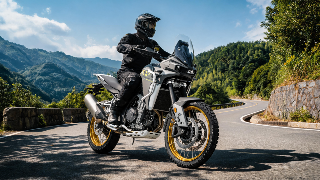 KOVE 800X Pro grise à jantes dorées, pilote casqué à l'arrêt dans un virage de route de montagne