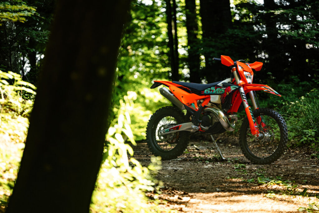 KTM 300 EXC Six Days 2027 garée sur sa béquille dans un chemin forestier