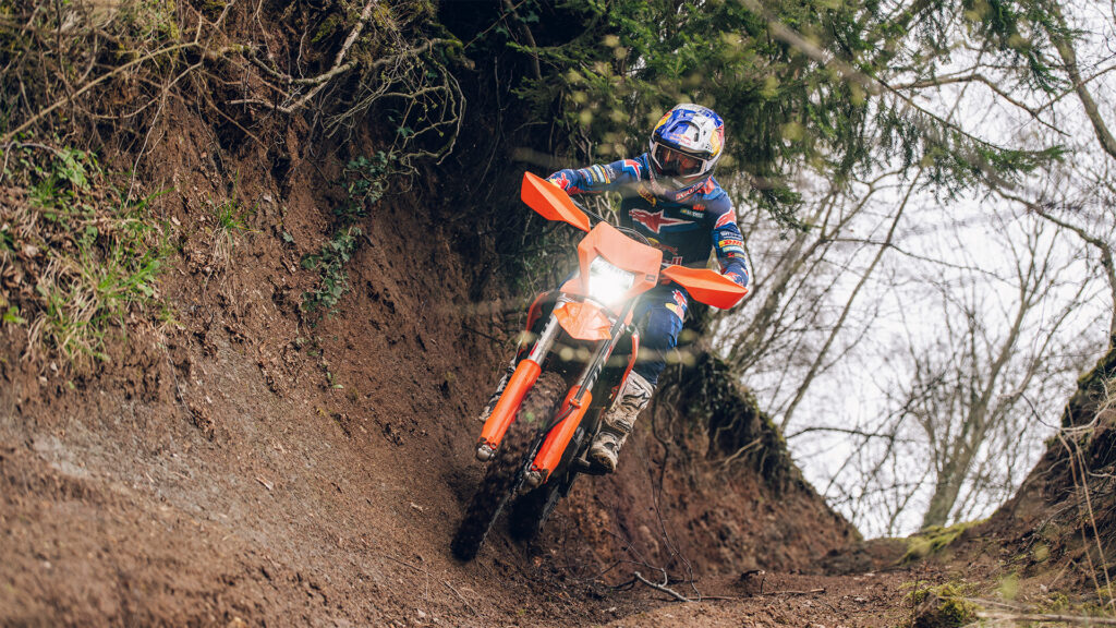 KTM 350 EXC-F 2027 dans un chemin creux en sous-bois, phare allumé