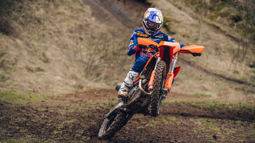 KTM 450 EXC-F 2027 en virage sur un terrain de terre, pilote Red Bull KTM Factory Racing