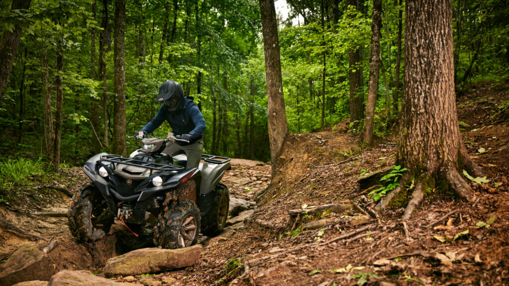 Yamaha Grizzly 700 EPS XT-R grimpant un passage boueux entre les arbres