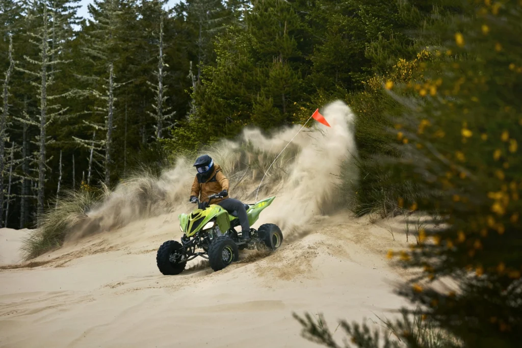 Yamaha Raptor 700R SE vert projetant du sable dans un virage en forêt
