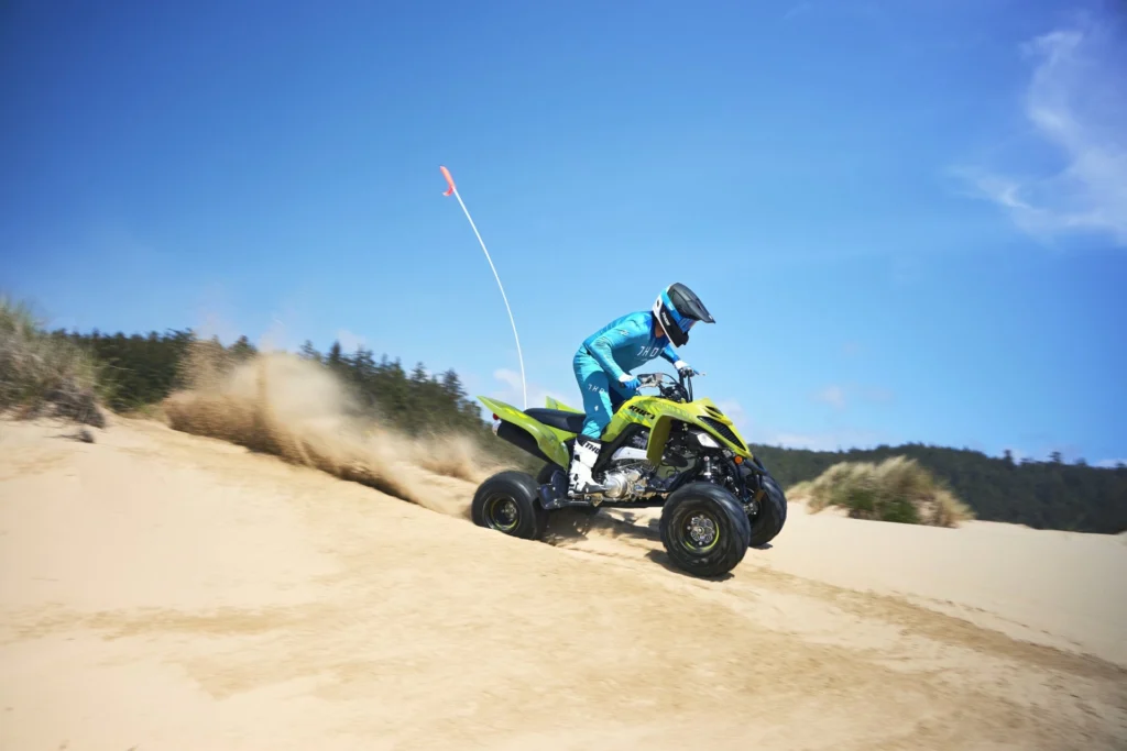 Yamaha Raptor 700R SE vert en appui dans le sable sous un ciel bleu
